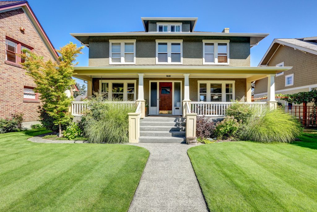 An image of a craftsman home. It is a square, two and a half story home with a large porch and front steps. 